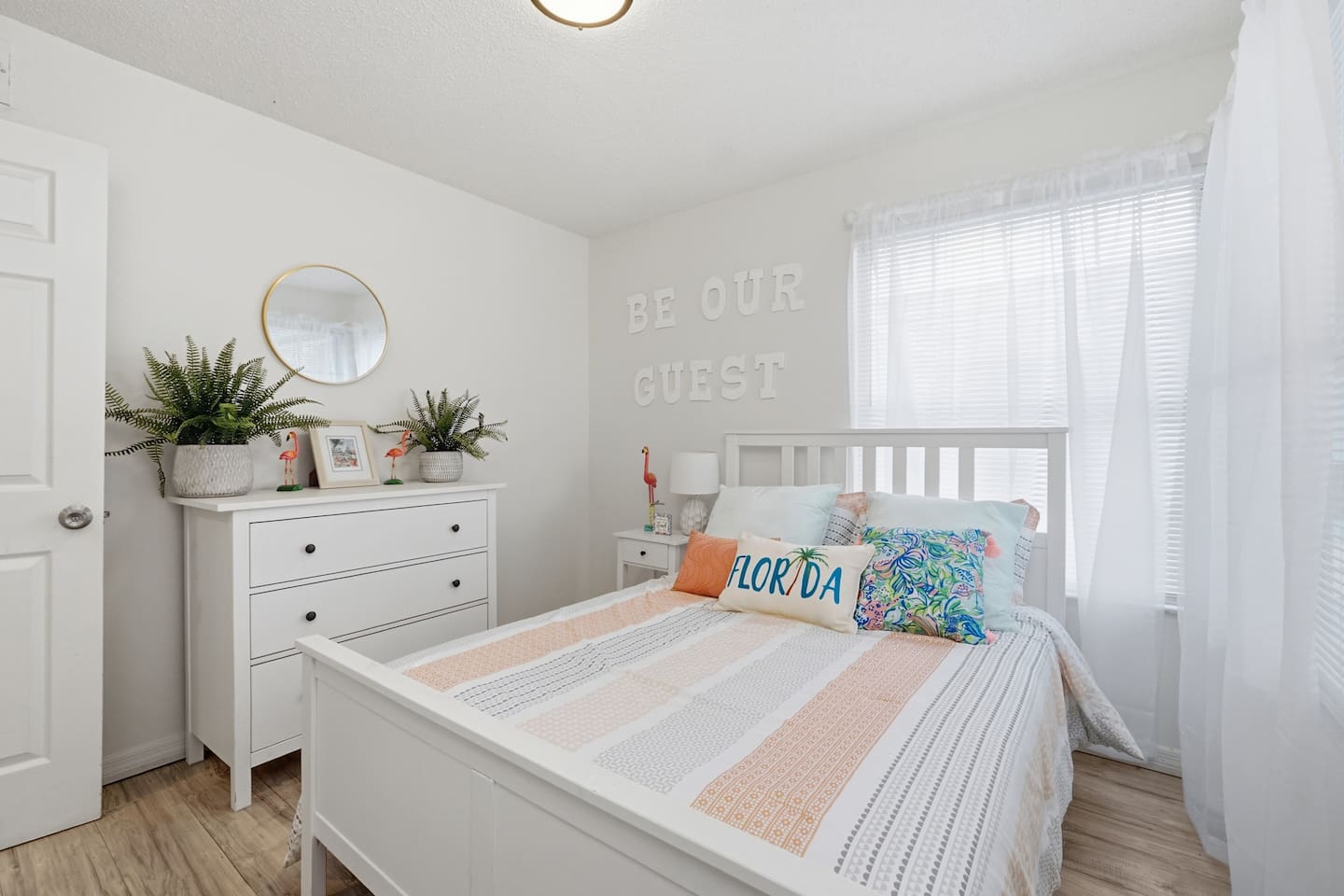 Bright bedroom with a queen bed and Be Our Guest wall decor at The Landing